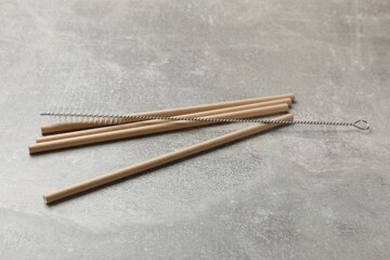 Bamboo drinking straws and cleaning brush on gray textured table