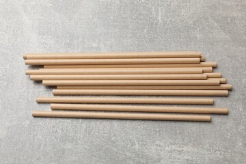 Bamboo drinking straws on gray textured table, top view
