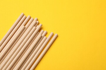 Obraz premium Bamboo drinking straws on yellow background, top view. Space for text