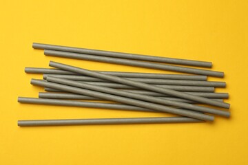 Bamboo drinking straws on yellow background, top view