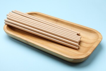 Bamboo drinking straws on light blue background, closeup