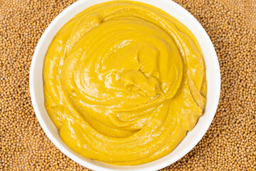 Mustard sauce and dry mustard seeds, top view.