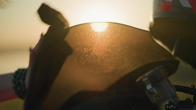 A close-up of a person s hand, adorned with a green bracelet, cleaning the windshield of a motorcycle