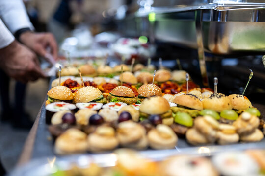 Assorted appetizers and gourmet sliders displayed at a catered event in an elegant venue during evening hours