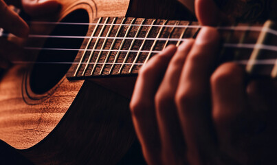 Fototapeta premium Close-Up of Hands Playing a Ukulele with Warm Lighting