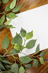 white sheet of paper on wooden background with leaves