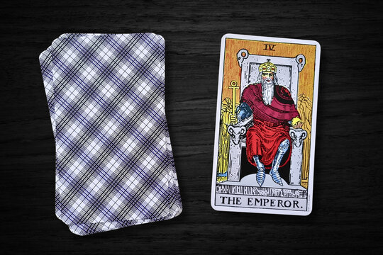 Carte de tarot "L'Empereur" du jeu Rider-Waite, pos&eacute;e sur un fond en bois sombre. Elle symbolise l'autorit&eacute;, la stabilit&eacute; et le pouvoir, avec l'image d'un empereur assis sur un tr&ocirc;ne.