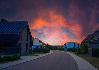 Fototapeta premium Modern luxury Villa on sunset. Street Road in Contemporary Residence with Barnhouse. Modern Barn house. Barn home in courtyard in sustainable enviroment. Family House in Gated Community
