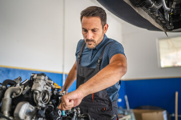 Car mechanic work on a car engine in an auto repair workshop