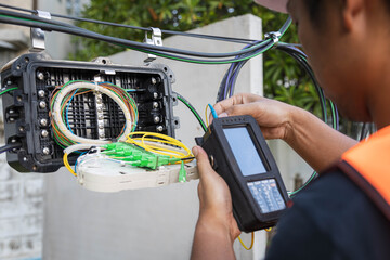 Engineer or technician checking fiber optic cables in internet splitter box.Fiber to the home...