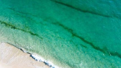 Aerial view of the beautiful turquoise sea with algae in Comporta, Portugal