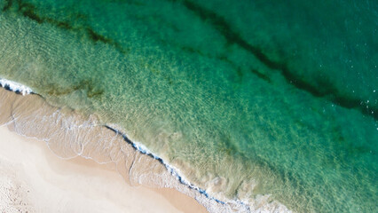 Aerial view of the beautiful turquoise sea with algae in Comporta, Portugal