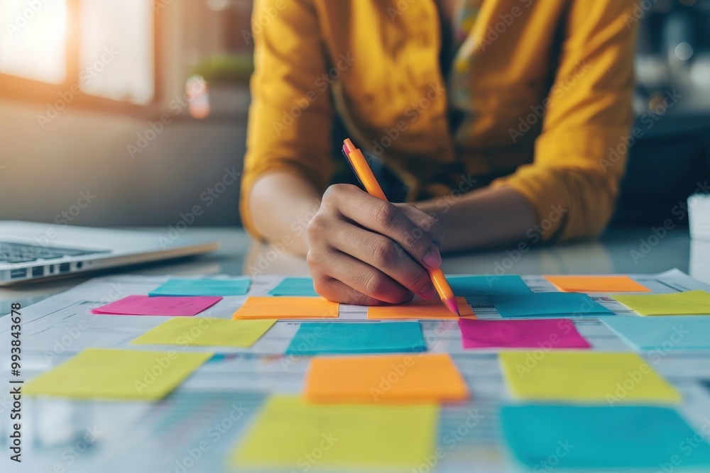 Poster close-up of a person writing on colorful sticky notes with a pen during a brainstorming session, sur
