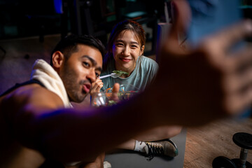 Two men and women are eating a vegetable salad together after exercising..