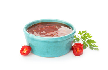 Hot chili sauce in bowl, parsley and cut pepper isolated on white
