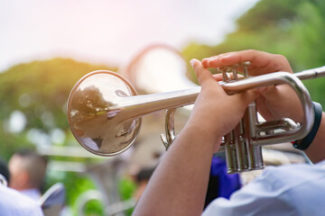 Man playing trumpet in public park. Close up of male hands playing trumpet.