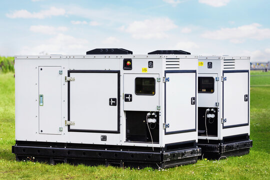 Set two large portable industrial power fuel generator green lawn at commercial event outdoors clear blue sky background. Mobile electricity supply energy plant unit backup equipment rent service