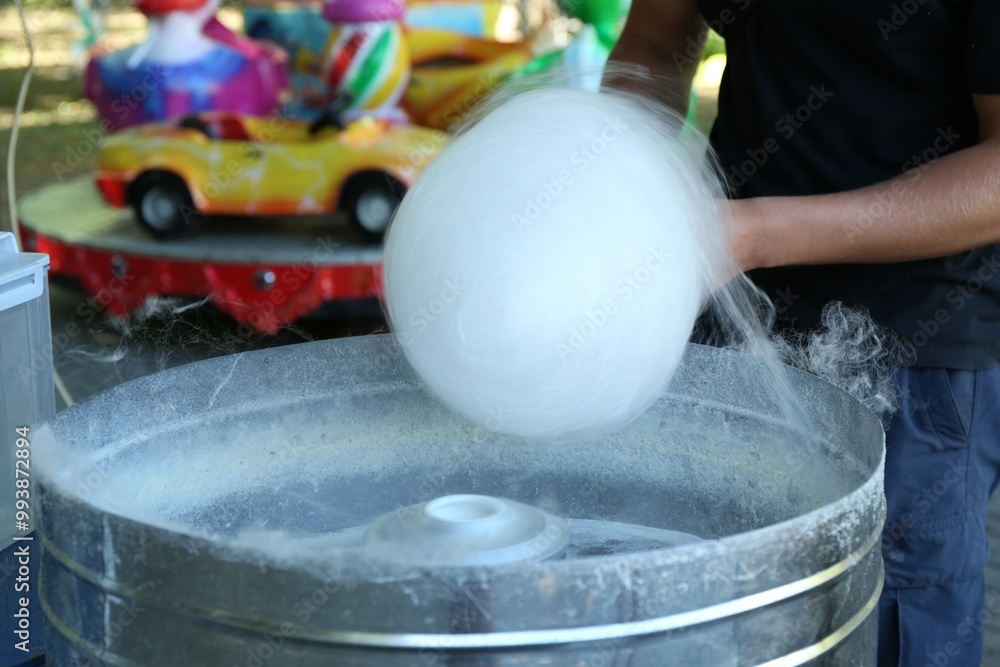 Poster Man making cotton candy with machine outdoors, closeup