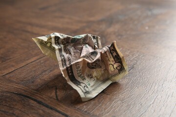 One crumpled dollar banknote on wooden table, closeup