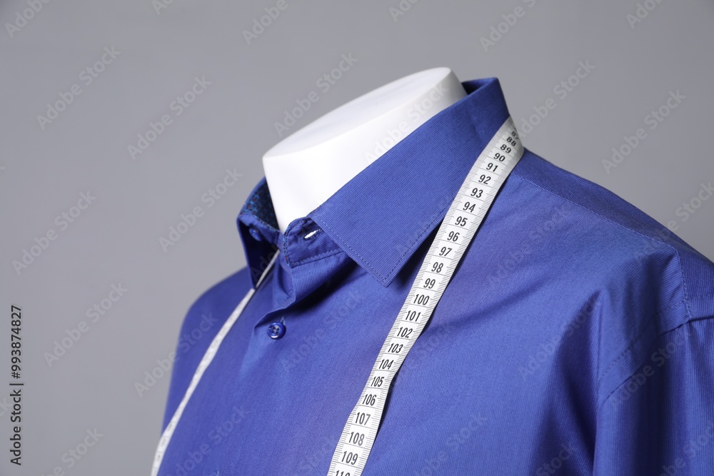 Wall mural Male mannequin with blue shirt and measuring tape on grey background, closeup