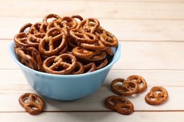 Tasty pretzel crackers on light wooden table, closeup