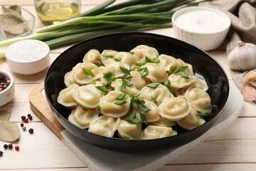 Delicious pelmeni with green onion served on wooden table, closeup