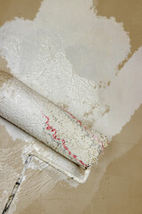 Creative graphic concept of paint roller applying fresh white paint onto the golden, beige, tan, brown color concrete wall. Process of home renovation, improvement and makeover. Copy space.