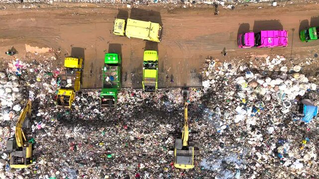 Aerial top view of A Huge Waste, garbage, dump, rubbish landfill. A landfill compactor, group of workers sort out the garbage in the landfill. Trash trucks dump waste polluting products.