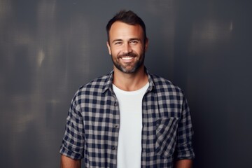 Obraz premium Portrait of a satisfied man in his 30s dressed in a relaxed flannel shirt over minimalist or empty room background