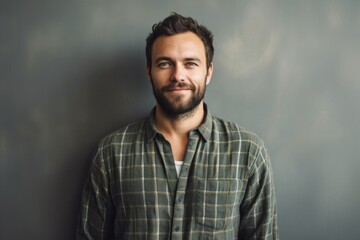Fototapeta premium Portrait of a satisfied man in his 30s dressed in a relaxed flannel shirt in minimalist or empty room background