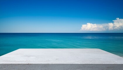 Fototapeta premium Concrete table top against the background of the sea on the beach. Empty white countertop for product presentation with blue water and sky. Outdoor mockup