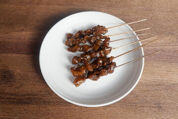 a plate satay with soy sauce and vegetables on it. Indonesian food.