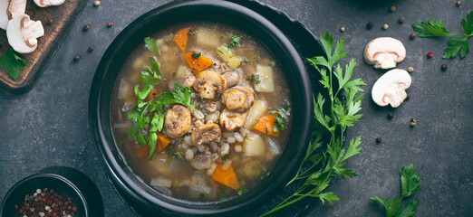 Mushrooms transparent healthy soup with champignon, vegetables and pearl barley. Simple, full of vegan proteins cuisine for the cold season. Forest food. Baltic , Scandinavian cuisine, banner