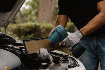 Obraz premium Mechanic Replacing Car Air Filter: A close-up shot of a mechanic's hands, wearing protective gloves, replacing the air filter in a car engine.
