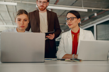 A diverse team is collaborating energetically on their laptops in a contemporary and dynamic office environment