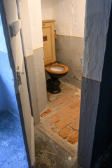 An old flush toilet with a crumbling wooden board.
