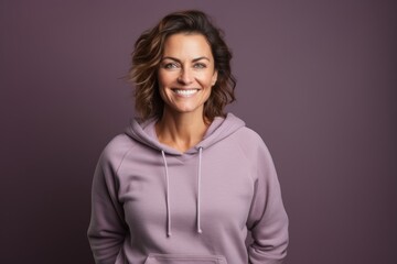 Fototapeta premium Portrait of a grinning woman in her 40s dressed in a comfy fleece pullover while standing against solid color backdrop