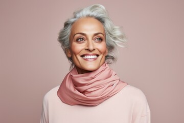 Fototapeta premium Portrait of a happy woman in her 50s wearing a versatile buff over solid color backdrop