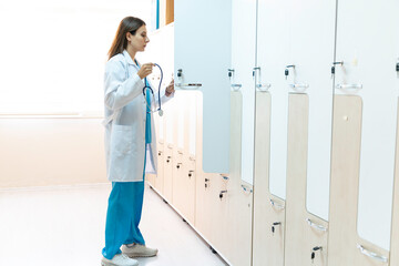 Young female doctor in a changing room putting his clothes to the locker