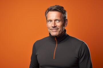 Fototapeta premium Portrait of a glad man in his 50s wearing a thermal fleece pullover in solid color backdrop