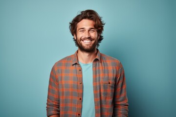 Fototapeta premium Portrait of a glad man in his 20s wearing a comfy flannel shirt isolated in solid color backdrop