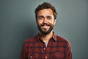 Fototapeta premium Portrait of a glad man in his 20s wearing a comfy flannel shirt in front of solid color backdrop
