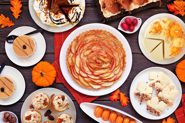 Autumn desserts table scene with an assortment of gourmet fall sweet foods. Above view over a dark wood background.