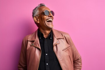 Obraz premium Portrait of a cheerful indian man in his 50s sporting a stylish leather blazer isolated in solid pastel color wall