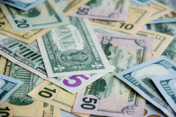 Big amount of US dollar bills in different nominations on table. Many dollar banknotes under natural light