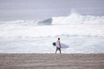 Surfer on the beach with his surfboard at Ribeira Grande, Sao Miguel, Azores