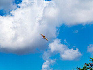 Yellow crop dusting aircraft flying over crops