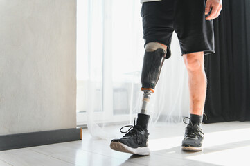 Unrecognizable man with bionic prosthetic leg at home indoors, copy space