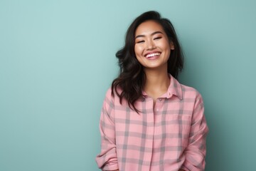 Fototapeta premium Portrait of a blissful asian woman in her 20s wearing a comfy flannel shirt isolated on solid pastel color wall