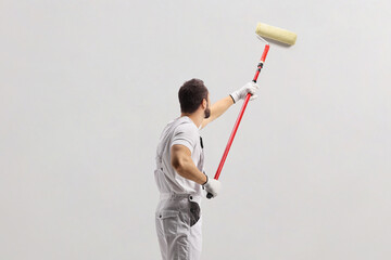 Painter using a paint roller and painting a wall